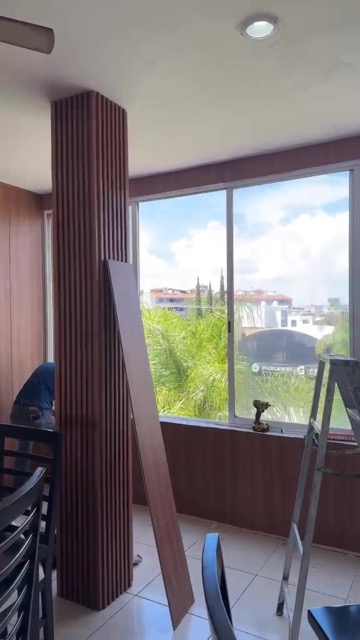 Columna acanalada de madera a medio instalar, con herramienta de trabajo, foto real de obra